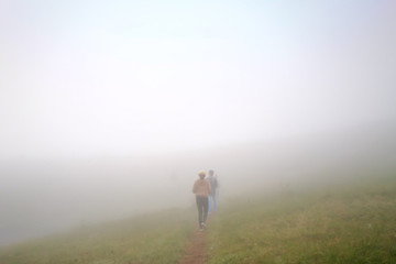 Fototapeta na wymiar White fog cover the People or traveler walk on the Mountain hill with grass field or white clouds