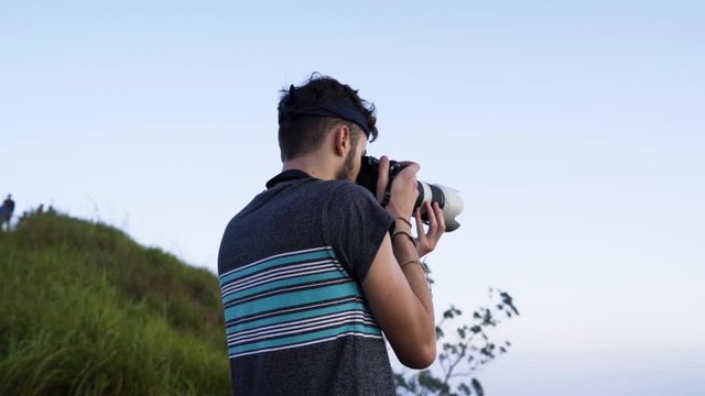 Young man taking handheld photos in a landscape environment
