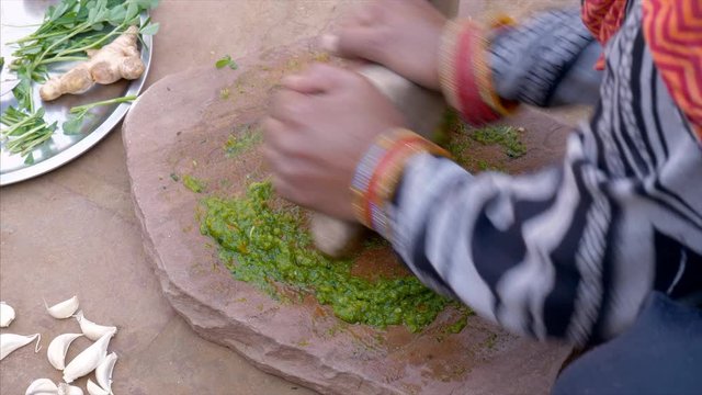 Indian woman using a stone to grind ingredients to make chutney outside her rural village house. Stock video of rural Indian woman using sil batta to prepare green chutney at her home. Traditional ...