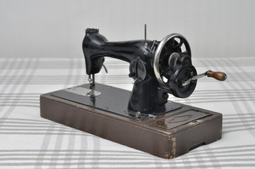 Vintage sewing machine with manual drive on the background of a linen tablecloth.