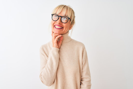 Middle age woman wearing turtleneck sweater and glasses over isolated white background with hand on chin thinking about question, pensive expression. Smiling with thoughtful face. Doubt concept.