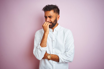 Young indian businessman wearing elegant shirt standing over isolated pink background looking...