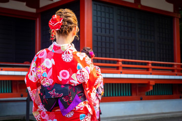 Fototapeta premium Japonia. Dziewczyna w czerwonym kimonie. Kobieta w kimonie stoi plecami. Młoda kobieta w buddyjskiej świątyni. Kobieta w krajowych japońskich strojach. Japonia retro. Tokio Japonia ludzie. Kup japońskie kimono
