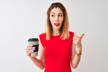 Young beautiful redhead woman drinking take away coffee over isolated white background pointing and showing with thumb up to the side with happy face smiling
