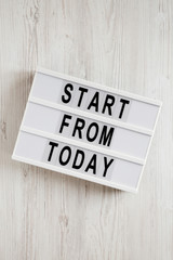 'Start from today' words on a modern board on a white wooden background, top view. Overhead, from above, flat lay. Close-up.