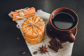 Homemade cookies and brown cup with coffee on dark background