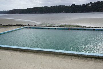 view of a beachfront pool and low tide in the harbor in Brittany, France