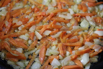 frying onions with carrots in a frying pan