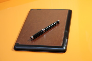 electric book and pen on a warm background