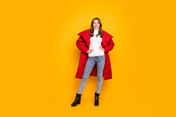 Full length photo of pretty lady traveler walking down street wear jeans leather shoes white pullover red long winter coat isolated yellow color background © deagreez