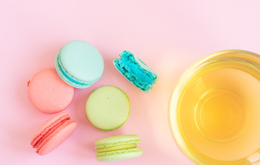 a Cup of green tea and colorful macaroons on a pink background