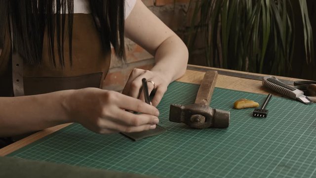 Press leather with hammer to make holes. Professional female skinner makes holes in leather. Handmade leather goods