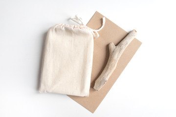 Mock up of tarot deck cotton bag with texture paper craft brown envelope and rustic stick on white background. Boho design of tarot cards pouch on white table with copy space for image or text.