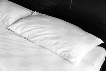 Fototapeta na wymiar White pillow lays at an empty bed