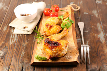 fried chicken leg on wooden board with pepper and herb