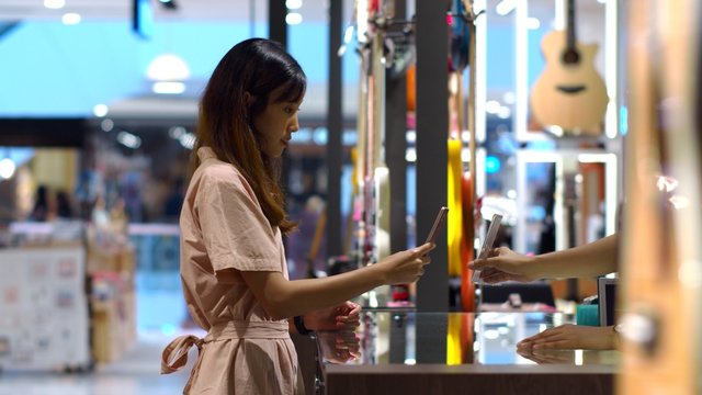 Young woman paying by scanning QR Code with smartphone