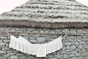 White clothes hanging on the stone wall of a rural house with a thatched roof (Madeira, Portugal, Europe)