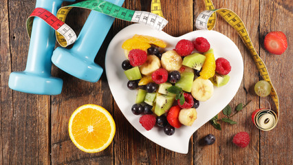 healthy food concept with fruit salad and dumbbell