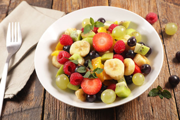 bowl with fresh fruit salad on wood background
