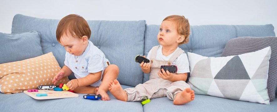 Beautiful toddlers sitting on the sofa playing with toys at home