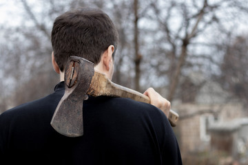 A man holds an ax in his hands against on black background
