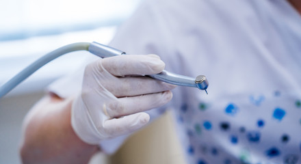 Stomatological instrument in dentists clinic. Doctor holding hand drill. Selective focus close up.