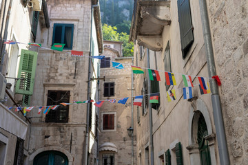Fototapeta na wymiar Montenegro - Flags of the various states decorating a narrow street in Kotor Old Town