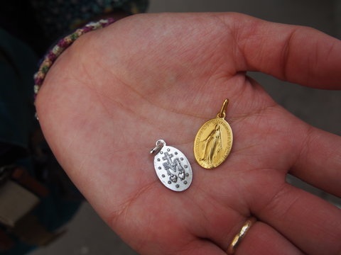 A woman holding a small gold and silver medal in her palm, Chapelle Notre-Dame de la medaille Miraculeuse, Paris, France