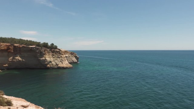pan right in portugal on algave coast blue sky and clear sea or ocean with cliffside very little clouds