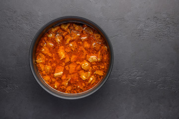 Homemade traditional Hungarian goulash dish in a saucepan against a dark background