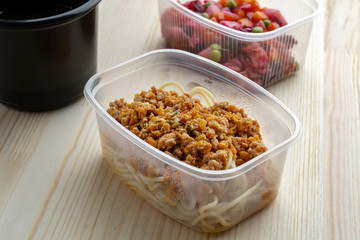 Pasta with minced meat and onion in navy-style and a jar of vinaigrette. Food from delivery.