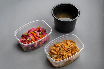 Pasta with minced meat and onion in navy-style and a jar of vinaigrette on a gray background. Food from delivery.
