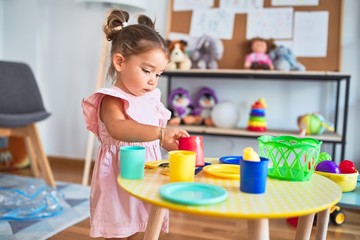 Young beautiful toddler playing with cutlery and food toys on the table at kindergaten