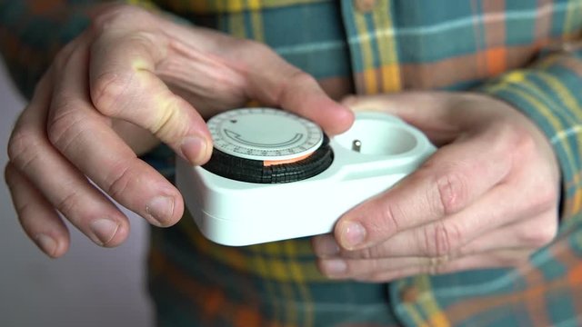 Man setting up plug-in timer switch