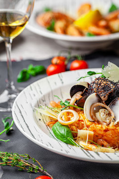 Italian food concept. Risotto with seafood, mussels, octopuses, squid. Serving dishes in a white plate. Modern serving in a restaurant. Background image. Copy space.