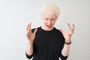 Young albino blond man wearing black t-shirt standing over isolated white background celebrating crazy and amazed for success with arms raised and open eyes screaming excited. Winner concept