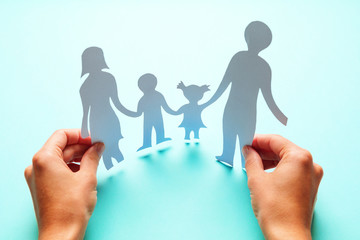 Paper family in hand isolated on blue background