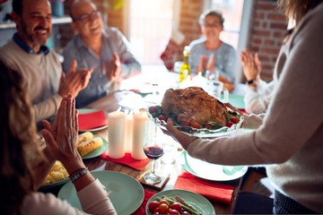 Family and friends dining at home celebrating christmas eve with traditional food and decoration, showing proud turkey cooking