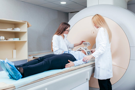 Radiologic two technician smiling help at mature female patient lying on a CT Scan bed