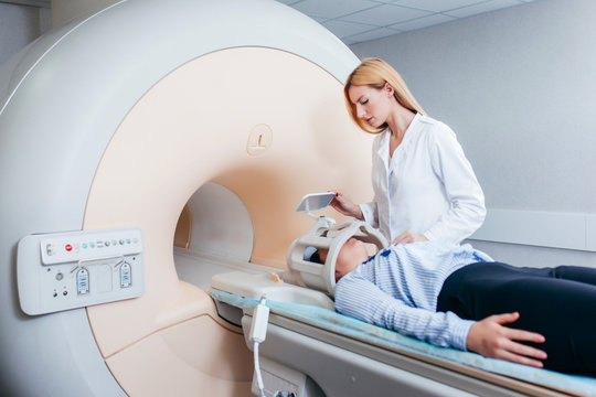 Radiologic blonde model technician help at mature female patient lying on a CT Scan bed