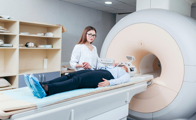 Radiologic model technician smiling help at mature female patient lying on a CT Scan bed