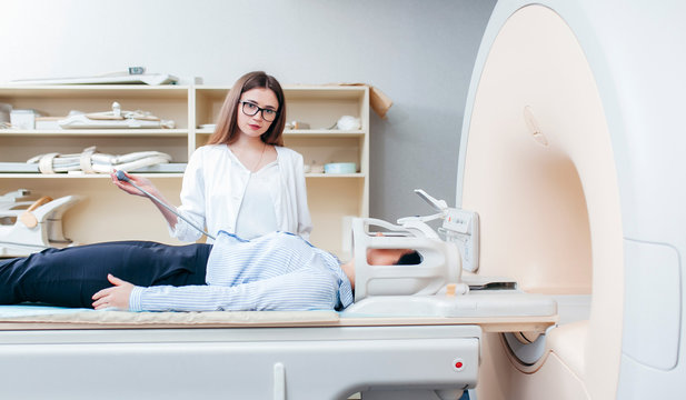 Radiologic model technician smiling help at mature female patient lying on a CT Scan bed