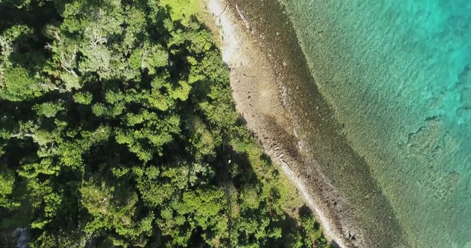 Aerial footage of ocean and land on an island in Tonga. Green lands and blue water