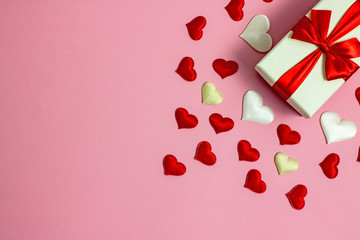 Valentine's Day background flat lay copy space. On a pink background red paper hearts, hearts made of white fabric and red satin. 