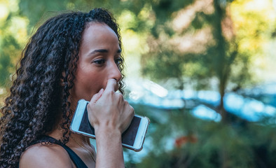 Black girl with the mobile in her hand scratching her face