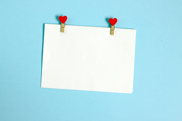 A sheet for congratulations on Valentine's Day. Valentine's Day flat lay copy space. Top view on a blue background a sheet of white paper for a text of congratulation and red hearts.