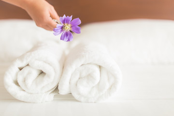 Fototapeta na wymiar A woman cleaning the hotel bed, with clean white towels and a flower decoration.