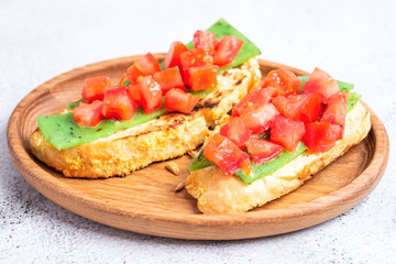 two Italian bruschettes with cheese and tomatoes on a wooden plate