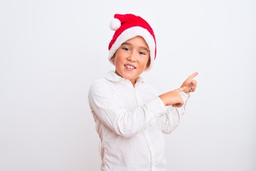 Beautiful kid boy wearing Christmas Santa hat standing over isolated white background smiling and looking at the camera pointing with two hands and fingers to the side.