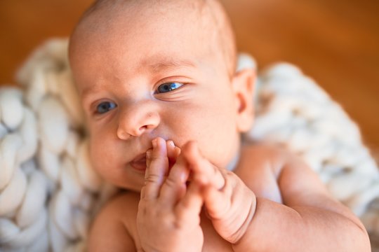 Adorable baby lying down on the floor over blanket at home. Newborn relaxing and resting comfortable